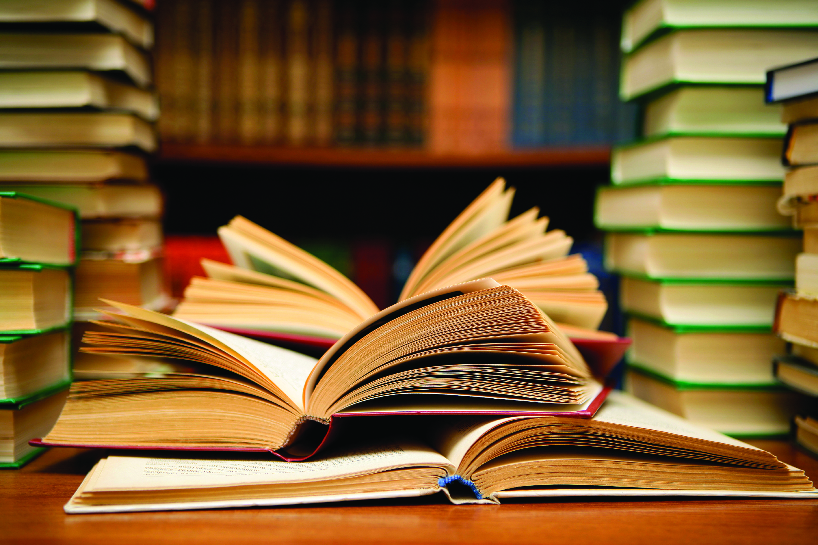 Bookstacks on a table with several open books.